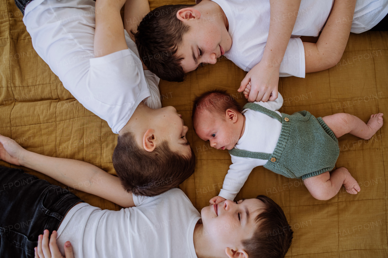 Three big brothers with their newborn brother lying in a bed.