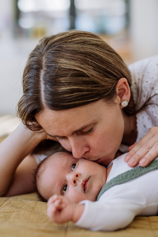 Portrait of woman kissing her newborn baby.