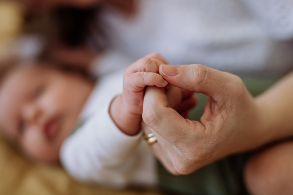 Close up of mother holding hand of her baby.