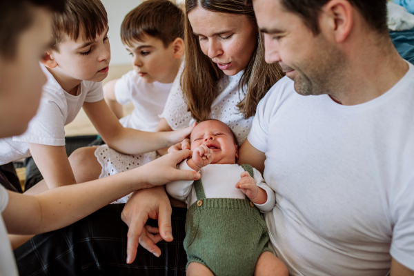 Big family with four sons enjoying their newborn baby.