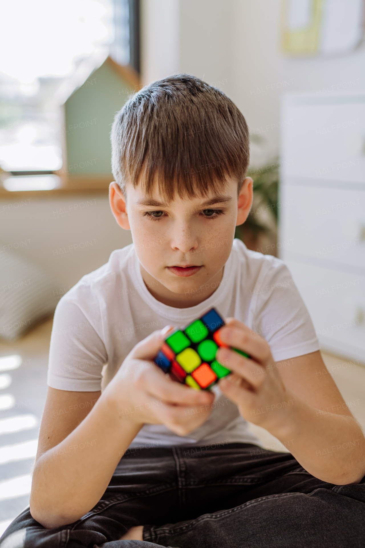 Little boy playing with Rubiks cube at home.