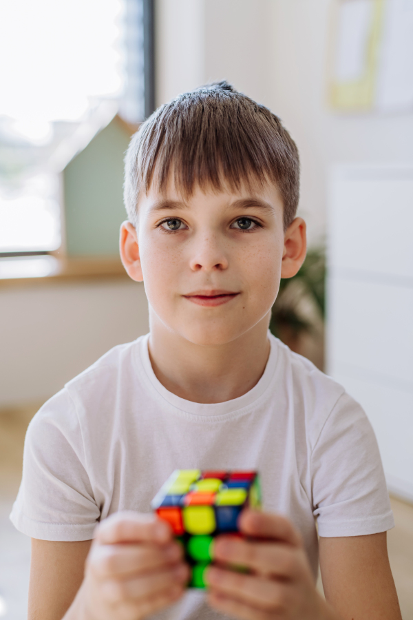 Little boy playing with cube at home.