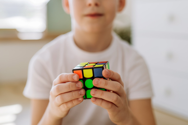 Little boy playing with Rubiks cube at home.