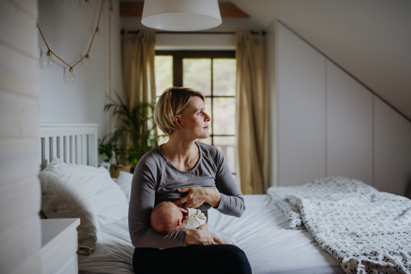 Mother brestfeeding her little baby in their bedrooom.