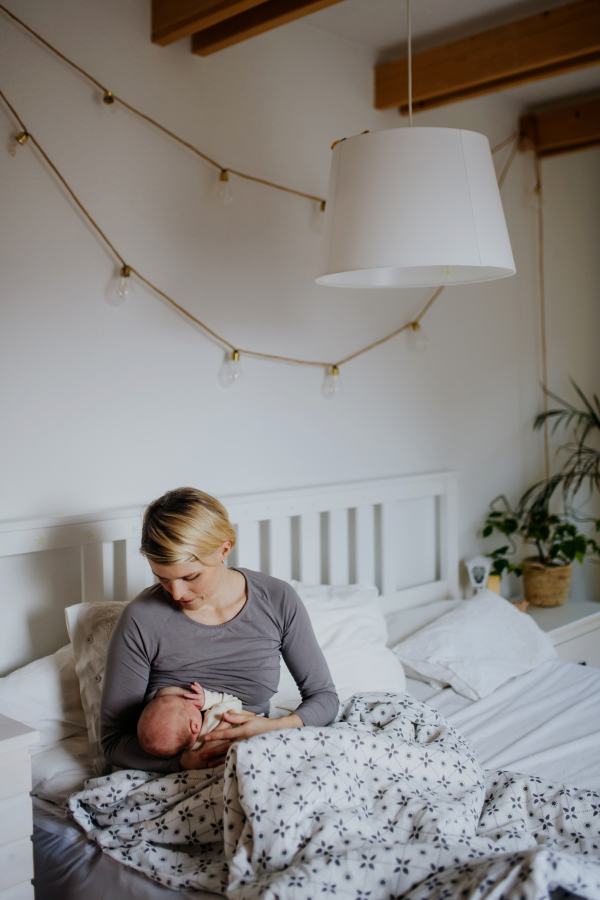 Mother brestfeeding her little baby in their bedrooom.