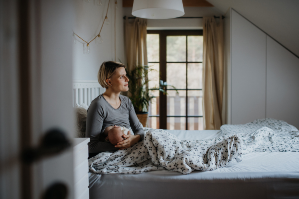 Mother brestfeeding her little baby in their bedrooom.