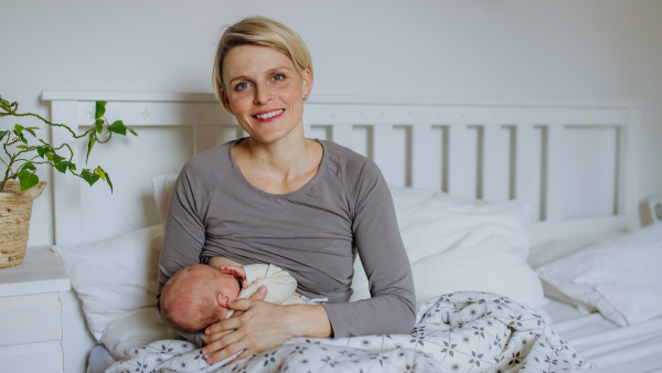 Mother brestfeeding her little baby in their bedrooom.