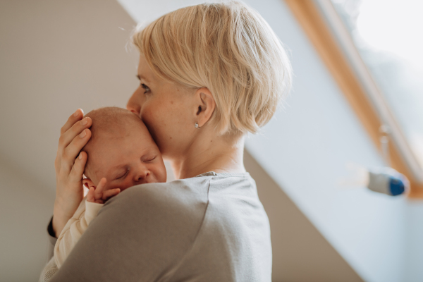 Mother cuddling her little newborn baby in their home.