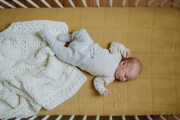 High angle view of sleeping newborn baby in little bed.