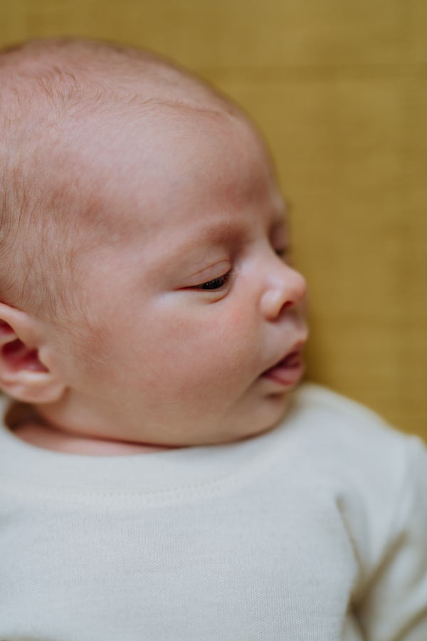 High angle view of sleeping newborn baby in little bed.