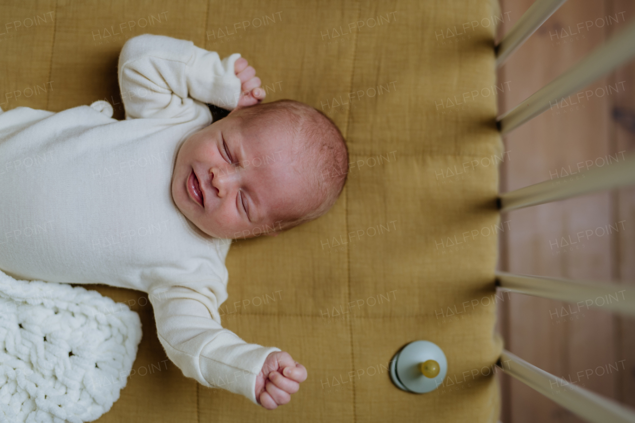 Top view of sleeping newborn baby in little bed.