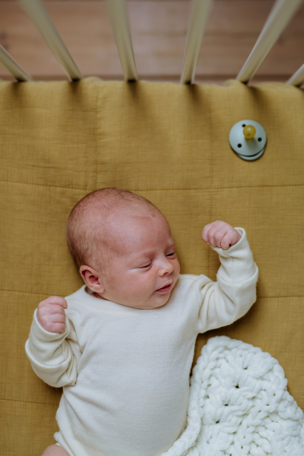 Top view of sleeping newborn baby in little bed.