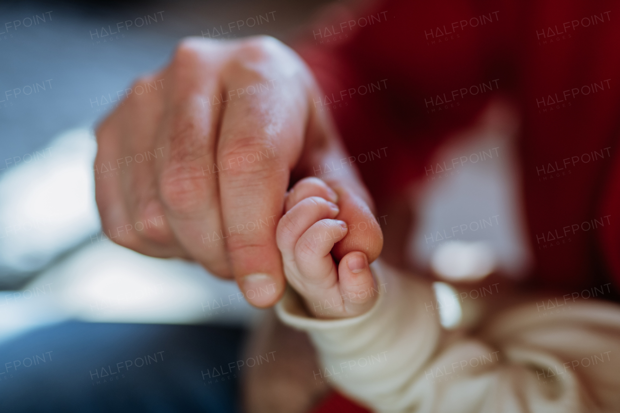 Close up of father holding hand of the newborn baby.