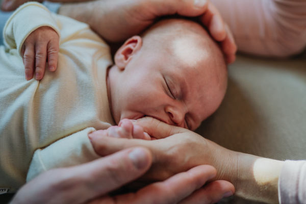 Close-up of parents cuddling their newborn crying son.