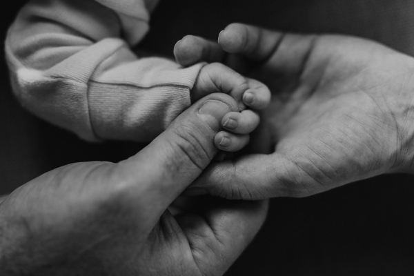 Close-up of parents holding hand of their newborn son, black and white image.