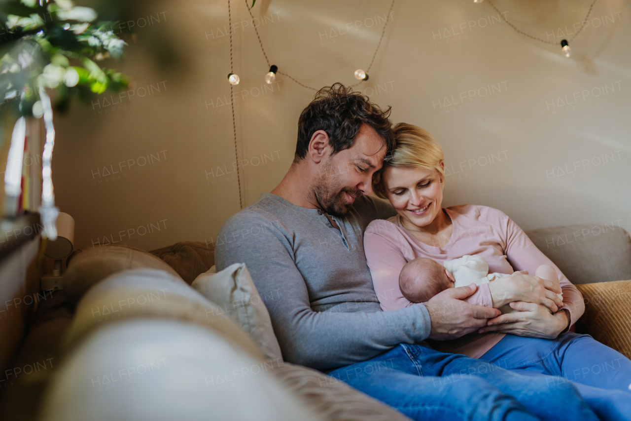 Parents holding their newborn son in their home.