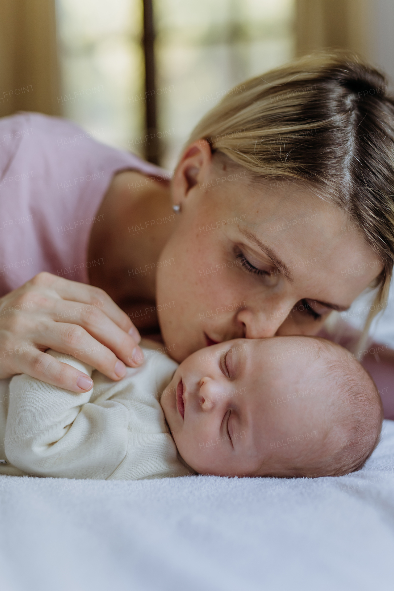 Mother cuddling her little newborn baby in their home.