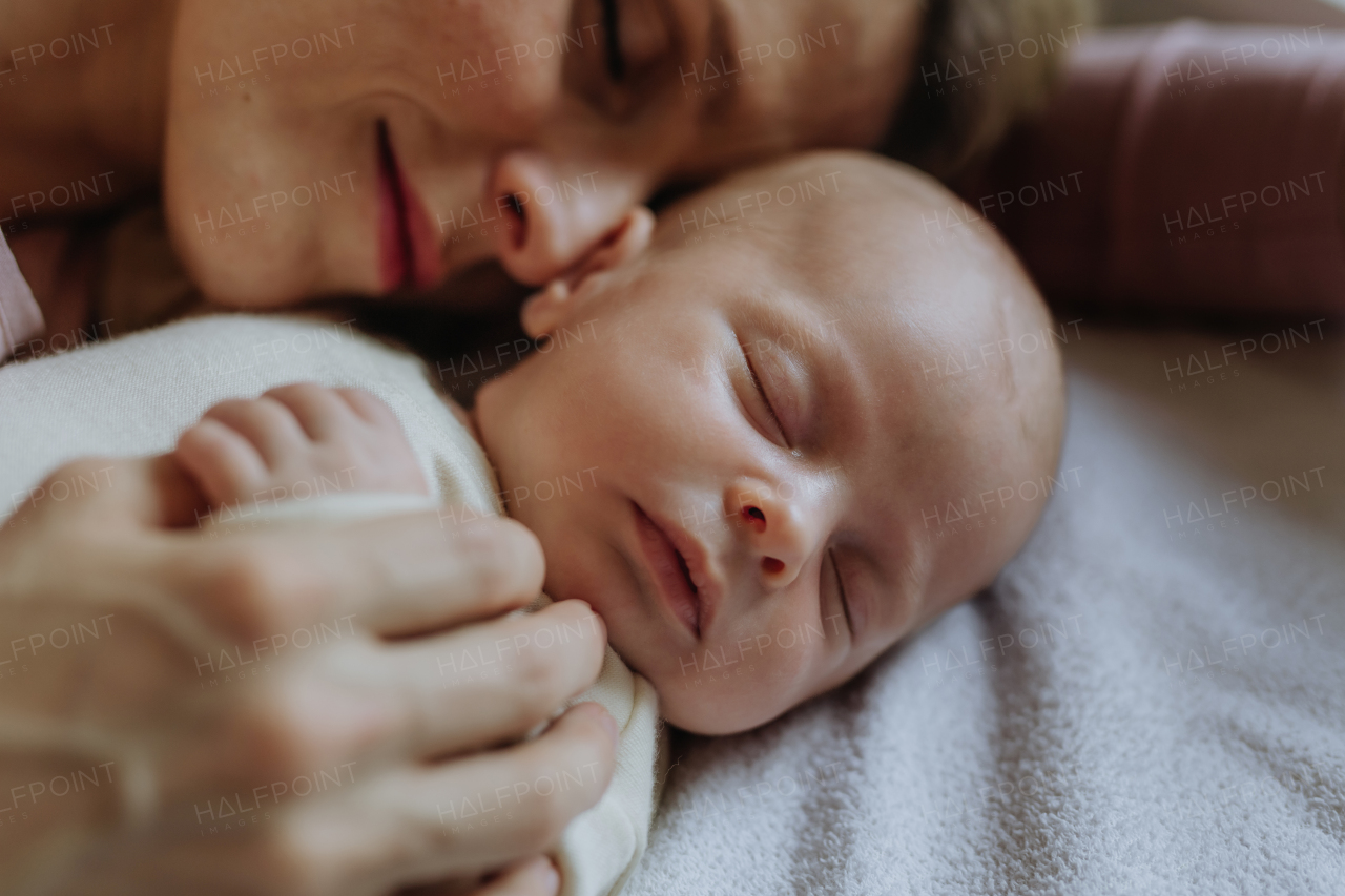 Close-up of mother cuddling with her newborn baby in the bad.