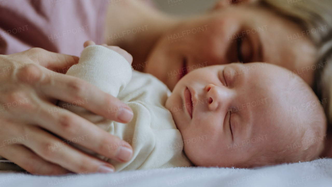 Mother cuddling with her newborn baby in the bed.