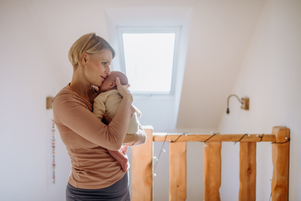 Mother cuddling her little newborn baby in their home.