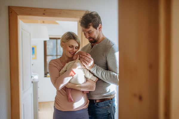 Parents holding their newborn son in their home.