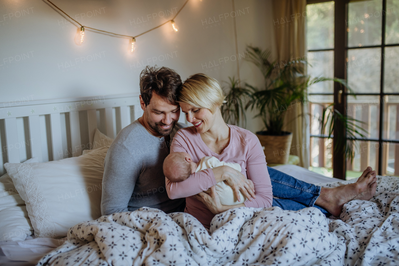 Parents holding their newborn son in their home.