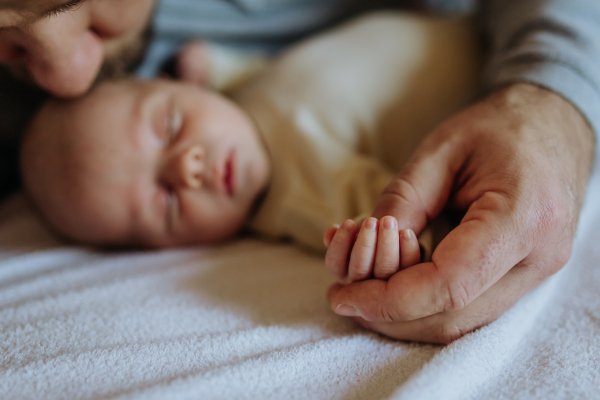 Close up of father holding hand of the newborn baby.