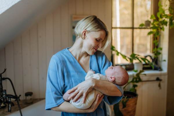 Mother cuddling her little newborn baby in their bathroom.