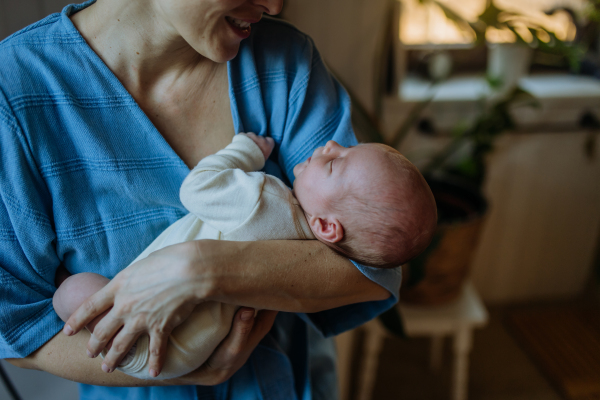 Mother cuddling her little newborn baby in their home.