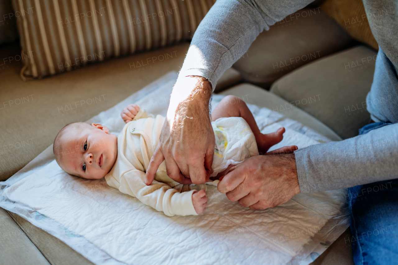 Mature father changing diaper his newborn baby.