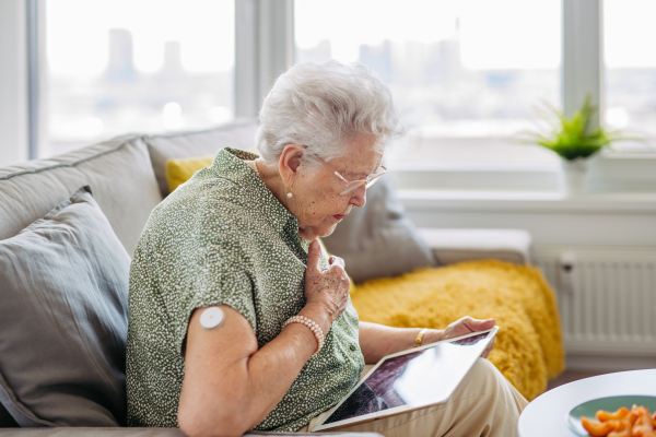 Diabetic senior patient with continuous glucose monitor feeling dizzy. Senior diabetic woman having low blood sugar. CGM device making life of elderly woman easier, helping manage her illness and focus on other activities.