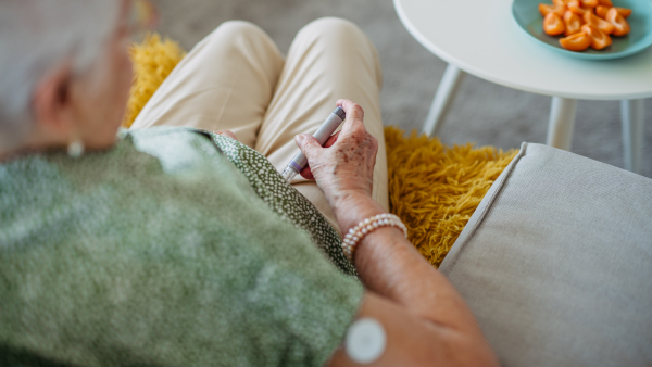 Diabetic senior patient injecting insulin in her belly. Close up of senior woman with type 1 diabetes taking insuling with syringe needle. Banner with copy space.