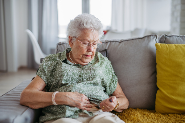 Diabetic senior patient injecting insulin in her belly. Close up of senior woman with type 1 diabetes taking insuling with syringe needle.