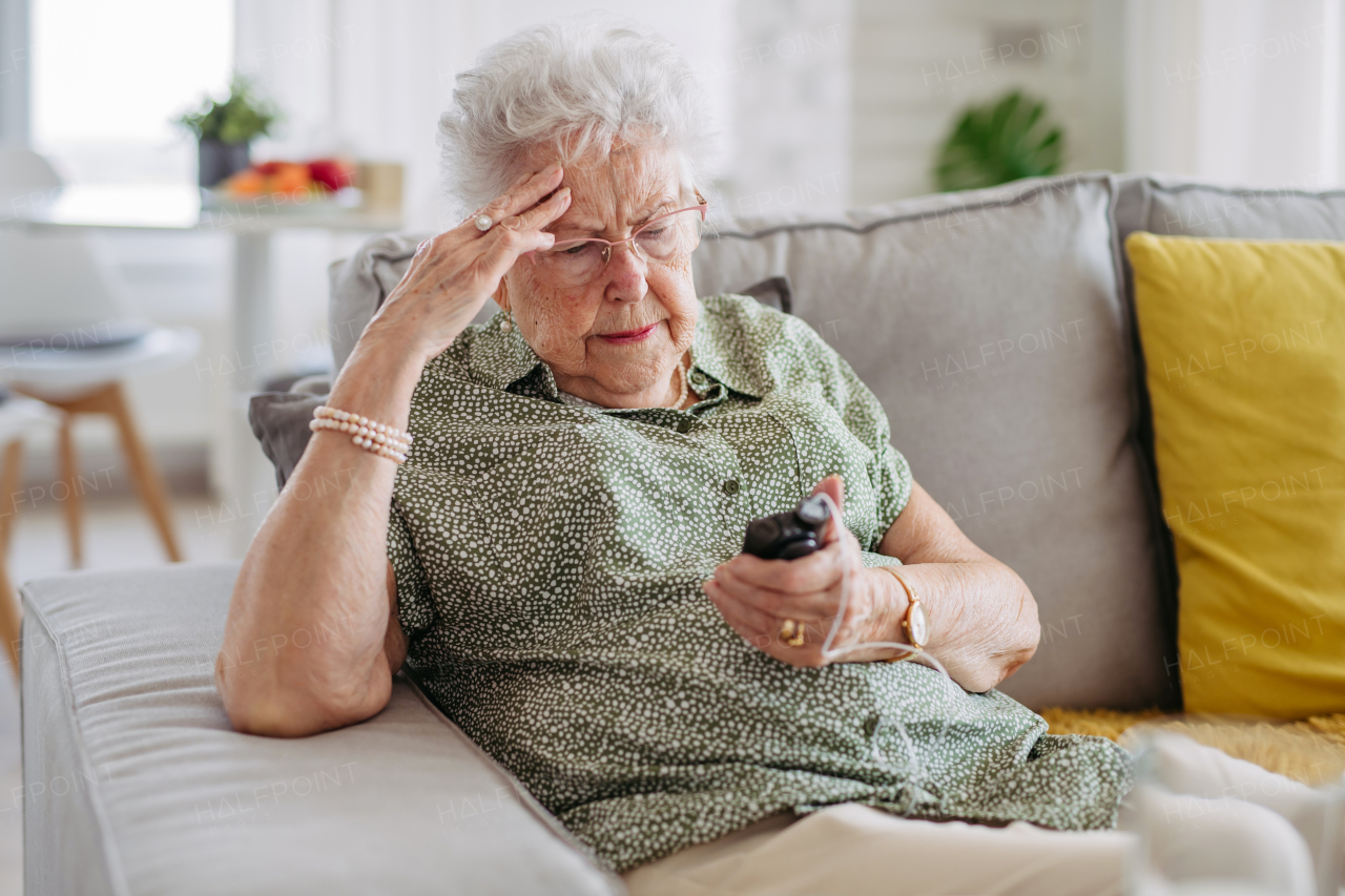 Diabetic senior patient checking her blood sugar level on insulin pump. Portrait of senior woman with type 1 diabetes taking insuling from tethered insulin pump.