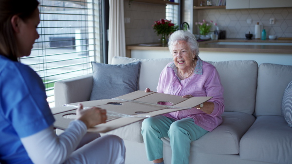 Nurse playing with senior woman, with ball and cardboard, homemade tabletop maze. Game activity for the elderly woman, helps with coordination and concentration.