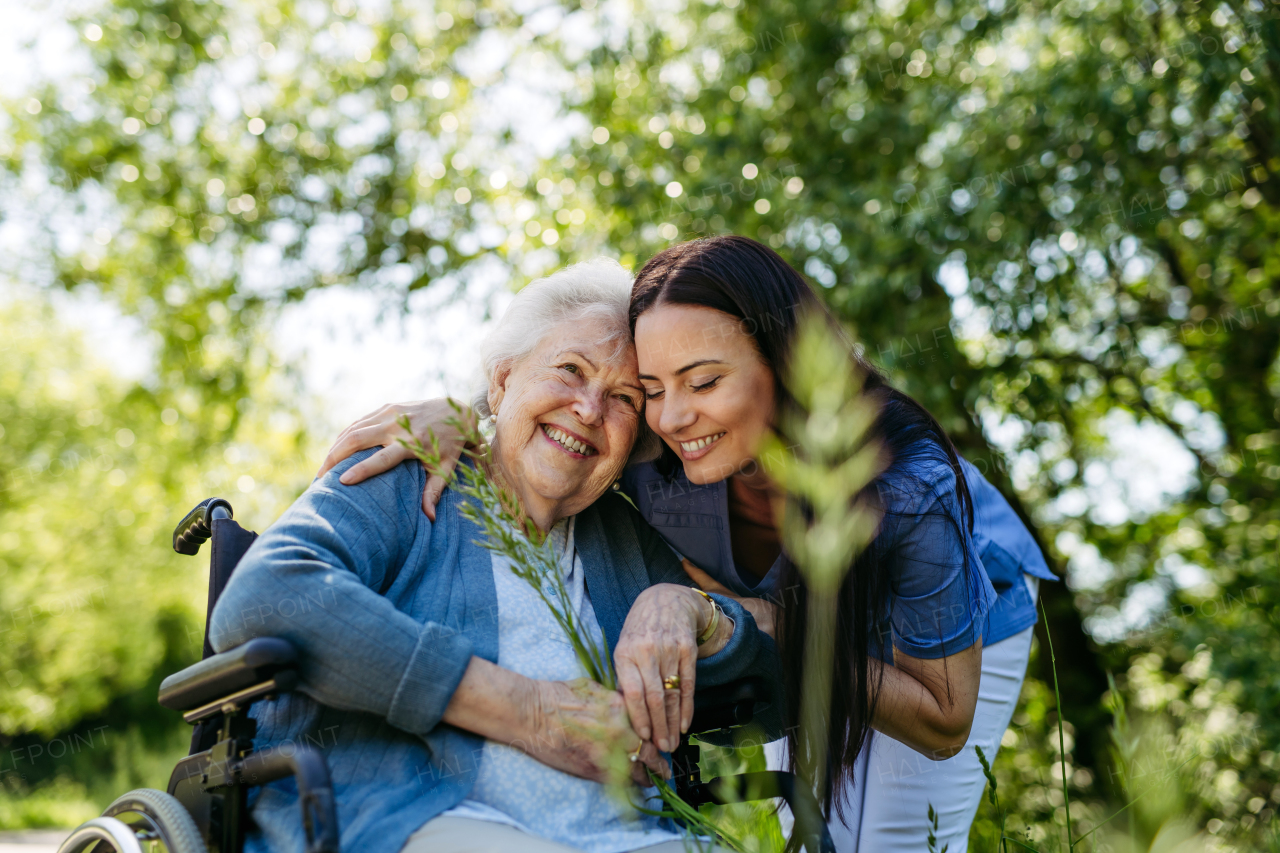 Caregiver pushing senior woman in wheelchair. Nurse and elderly woman enjoying a warm day in nursing home, public park.