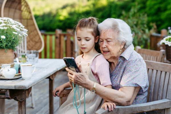 Granddaughter taking selfie with elderly grandma, companionship. Senior lady spending time with young girl, enjoying together time. Weekend in cottage.