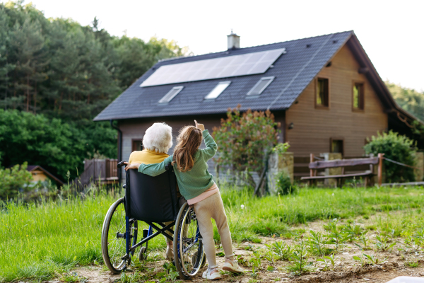 Granddaughter spending time with elderly grandma, companionship. Senior lady in wheelchair spending time in nature. Weekend in cottage.