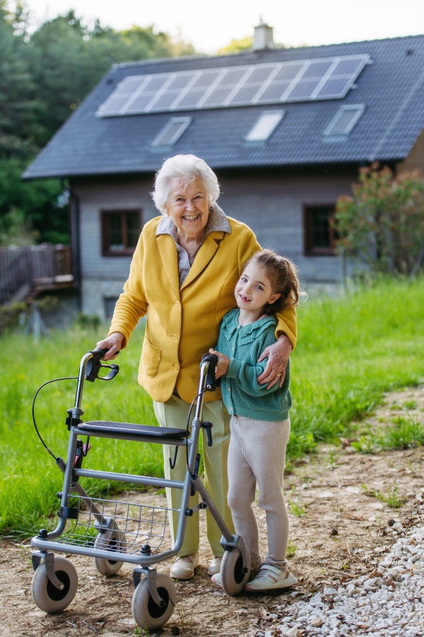 Granddaughter spending time with elderly grandma, companionship. Senior lady with walker spending time in nature. Weekend in cottage.