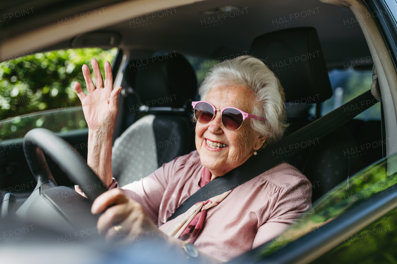 Happy senior woman driving car alone, enjoying the car ride. Safe driving for elderly adults, older driver safety. Driving license renewal at older age.