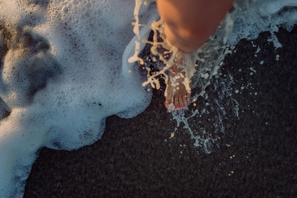 Woman walking on the beach during sunset, close-up of feet.