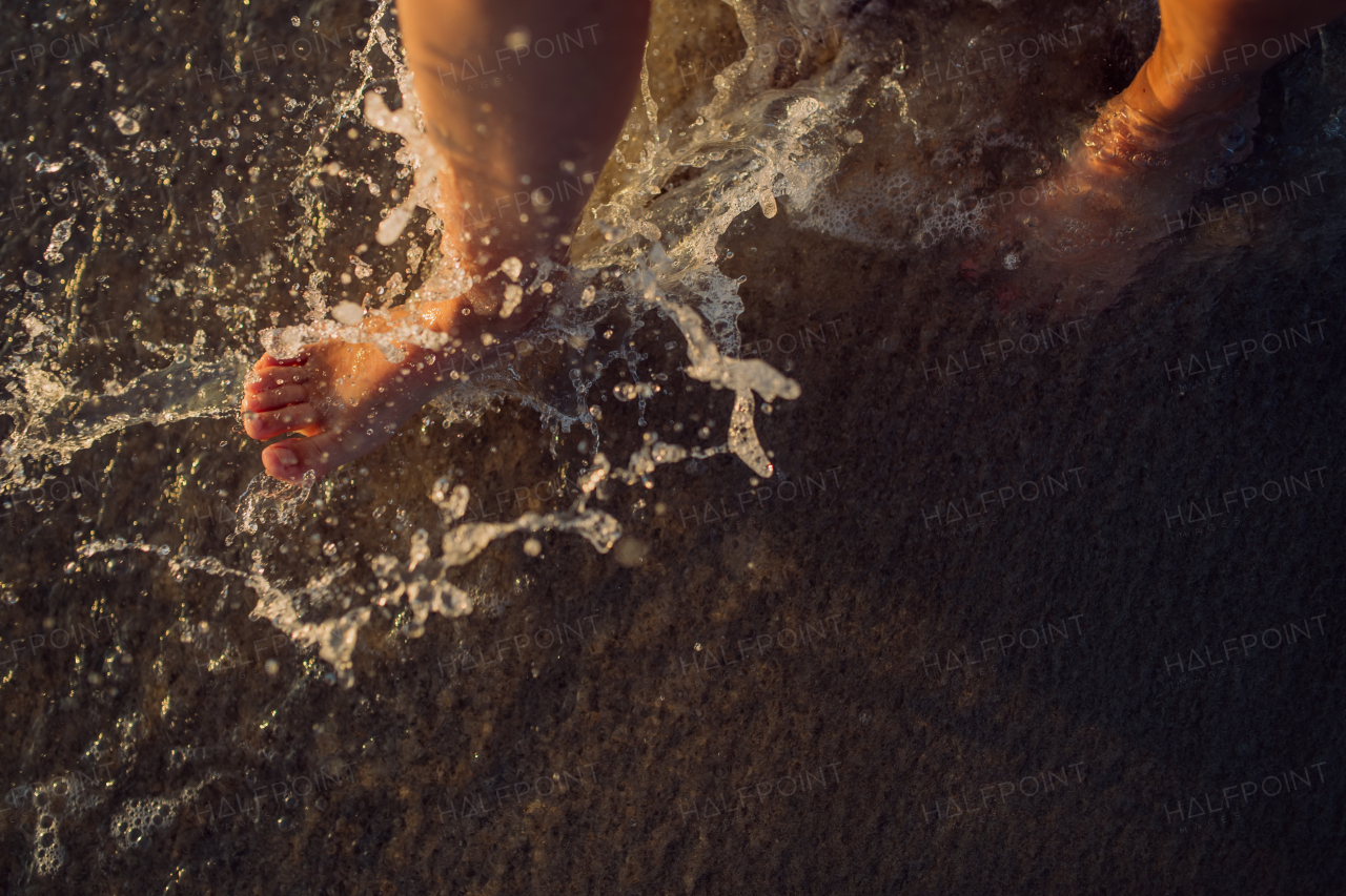 Woman walking on the beach during sunset, close-up of feet.