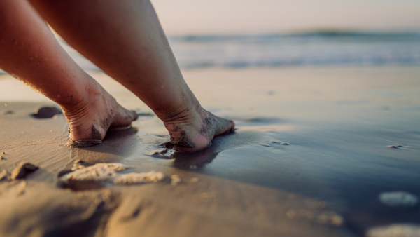 Close-up of woman with her feet in ocean.