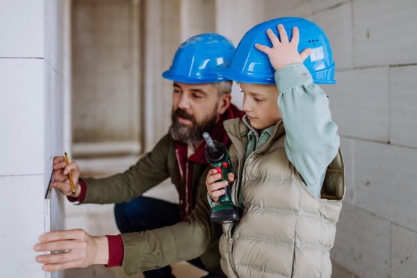 Father and his little son working together on their unfinished house.