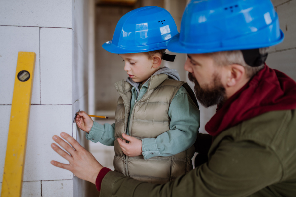 Father and his little son working together on their unfinished house.