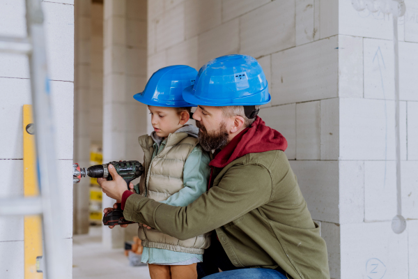 Father and his little son working together on their unfinished house.