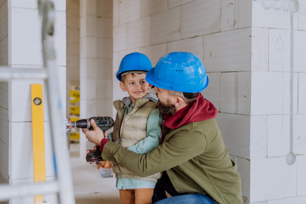 Father and his little son working together on their unfinished house.