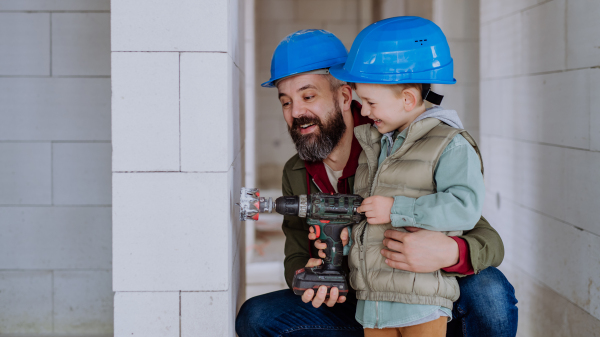 Father and his little son working together on their unfinished house.