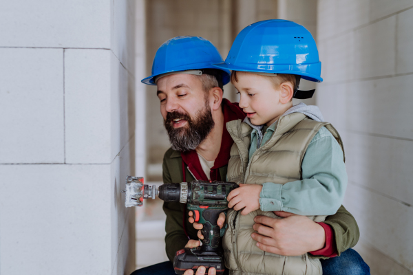 Father and his little son working together on their unfinished house.