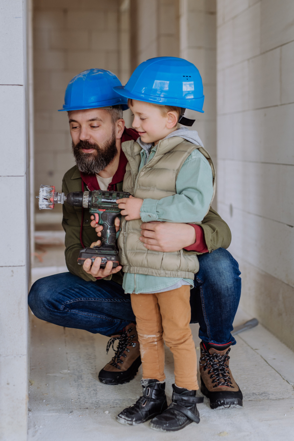 Father and his little son working together on their unfinished house.